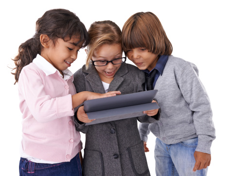 Studio shot of three kids standing and working on a tablet