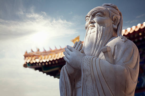 Close-up - stone statue of Confucius, pagoda roof in background stock photo