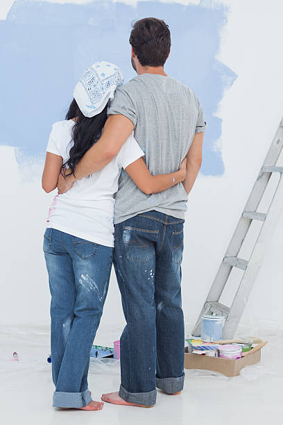 istock Cute couple looking at their wall painted in blue color 462637621