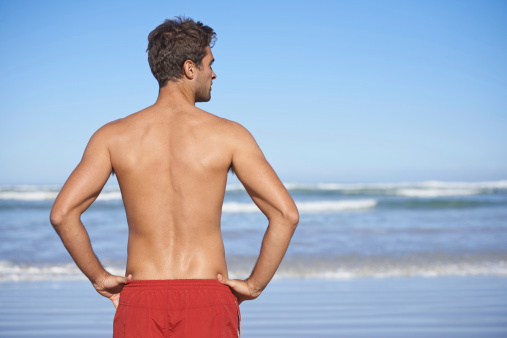 Rear-view of a male lifeguard looking out at the ocean