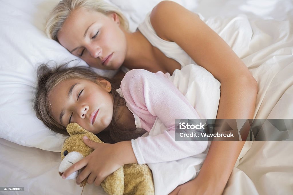 Madre abbracciare Sua figlia a letto - Foto stock royalty-free di Abbracciare una persona