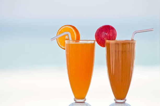 Two fresh fruit juices on a beach