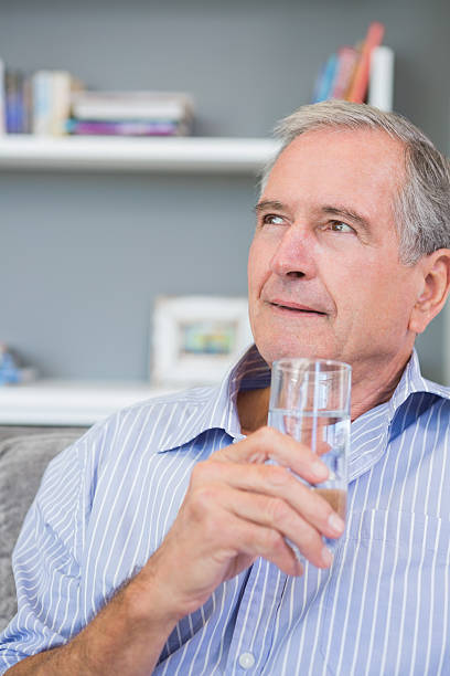 istock Mature man thinking and drinking water on his sofa 462642111