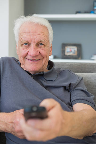 istock Smiling mature man sitting on sofa watching television 462646999