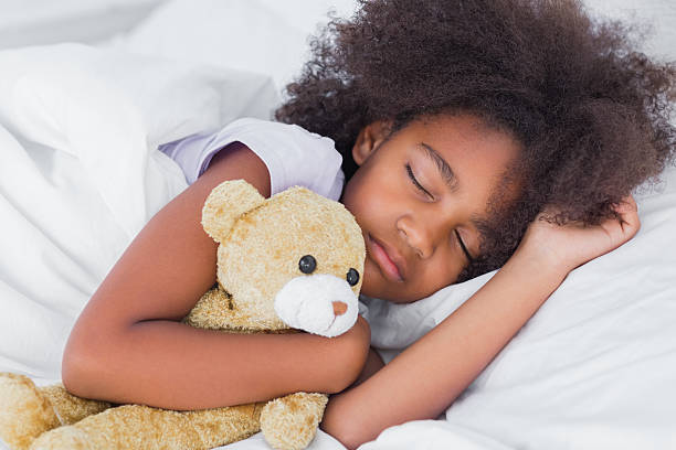 istock Cute little girl sleeping in bed cuddling teddy bear 462649191