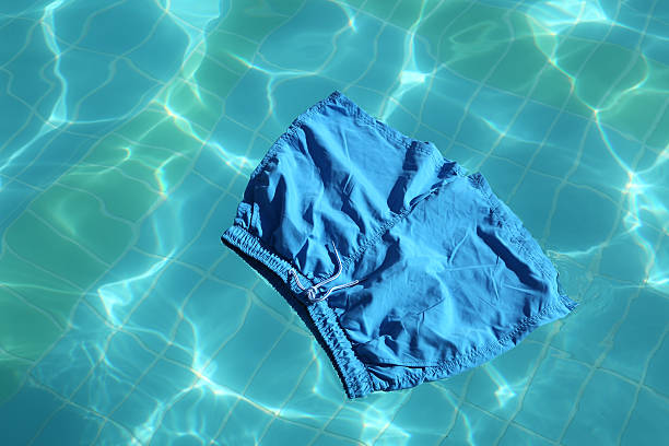 Vertical shot of a handsome young man sleeping shirtless on a towel in his backyard