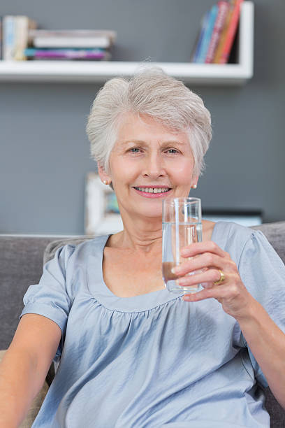 istock Smiling mature woman drinking water on her sofa 462672487