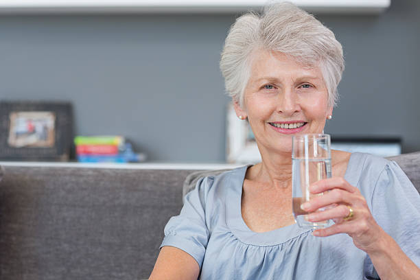 istock Mature woman drinking water on her sofa 462672493