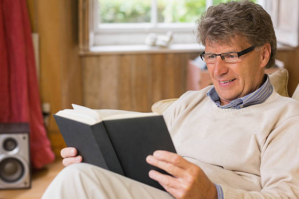 istock Calm mature man reading a book sitting on his sofa 462675827