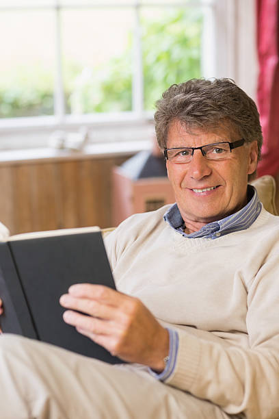 istock Relaxed mature man reading a book sitting on his sofa 462675843