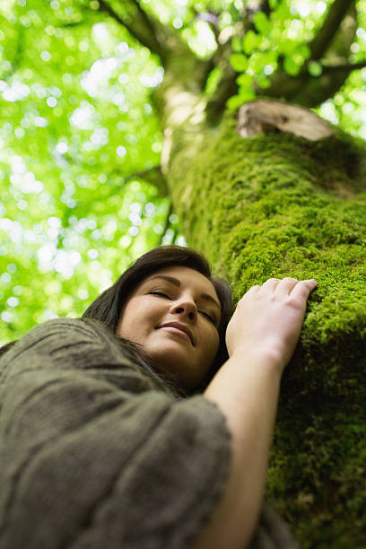 istock Peaceful young woman holding tree trunk 462681559