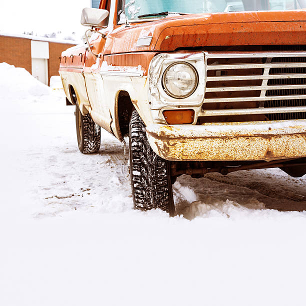 Old rusty truck under a pile of snow along a road in Northern Norway during winter.