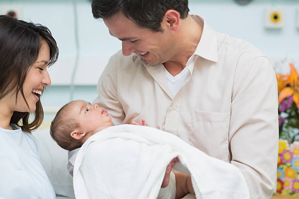 padre y madre sostiene un bebé riéndose mientras - hospital flower newborn 40s fotografías e imágenes de stock