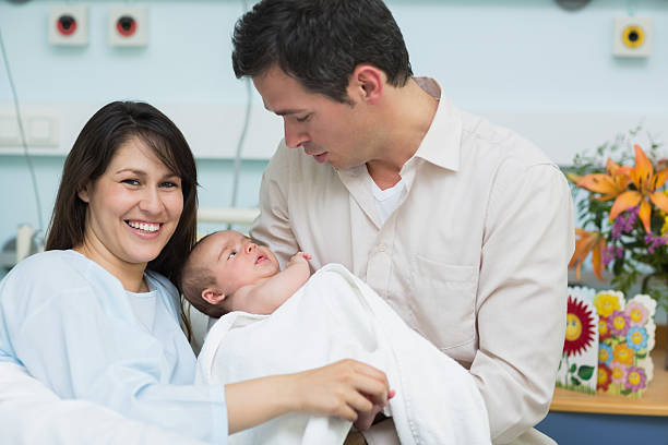 madre y padre sostiene un bebé - hospital flower newborn 40s fotografías e imágenes de stock