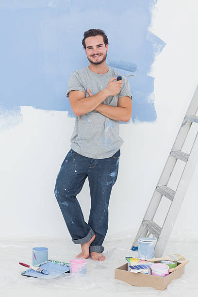istock Cheerful man with paintbrush in front of wall 462710665