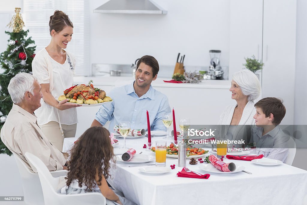 Woman bringing food at a christmas dinner Woman bringing food to her family at a christmas dinner Carrying Stock Photo