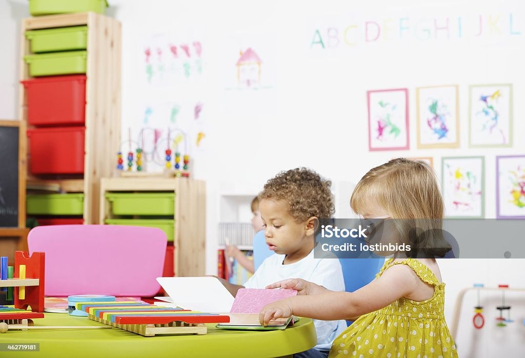 Toddlers Reading In A Nursery Setting A portrait of a pair of toddlers reading in a nursery setting. 2-3 Years Stock Photo