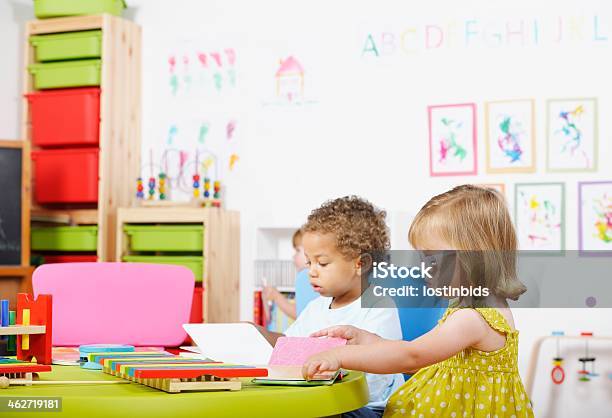 Toddlers Reading In A Nursery Setting Stock Photo - Download Image Now - 2-3 Years, Book, Boys