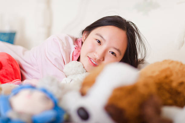 istock smiling girl lying on bed with her plush toys 462720659