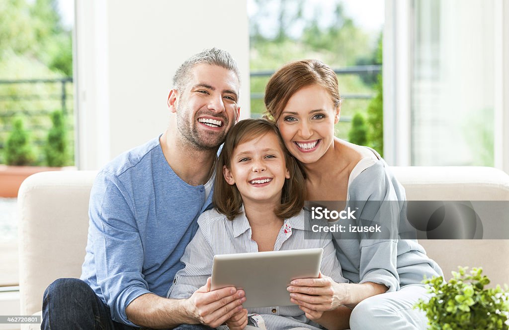 Happy family with digital tablet Happy parents with their daughter using a digital tablet, smiling at the camera. 10-11 Years Stock Photo