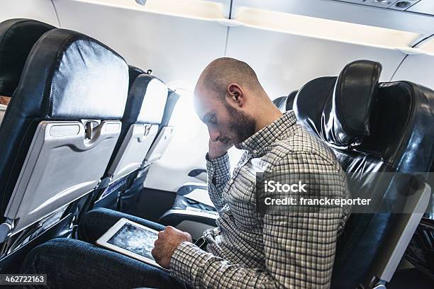 Pensive Business Man Using A Digital Tablet On The Plane Stock Photo - Download Image Now