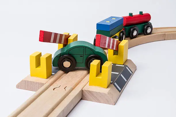 green toy car on railroad crossing with train coming