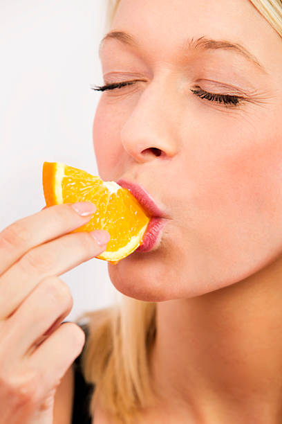 istock Blond woman eating Orange fruit - headshot 462765945