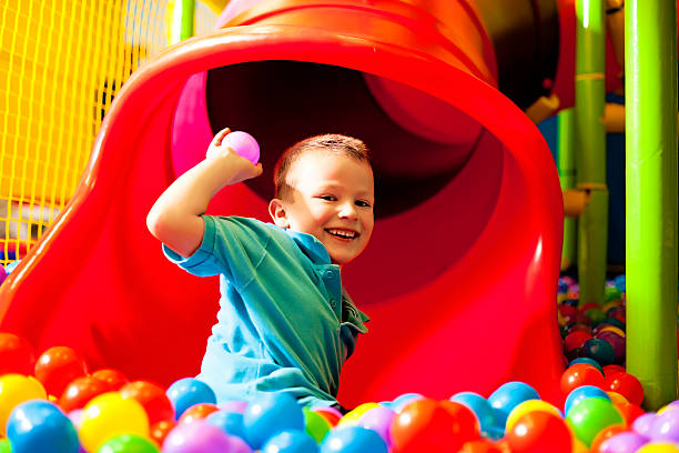 istock Young smiling boy playing in a ball pool next to a slide 462772821