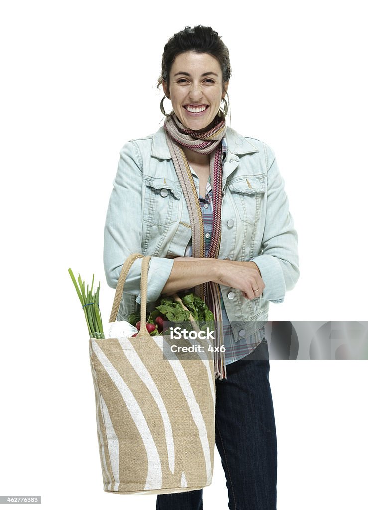 Allegro donna in piedi con un sacchetto di verdure - Foto stock royalty-free di Abbigliamento casual
