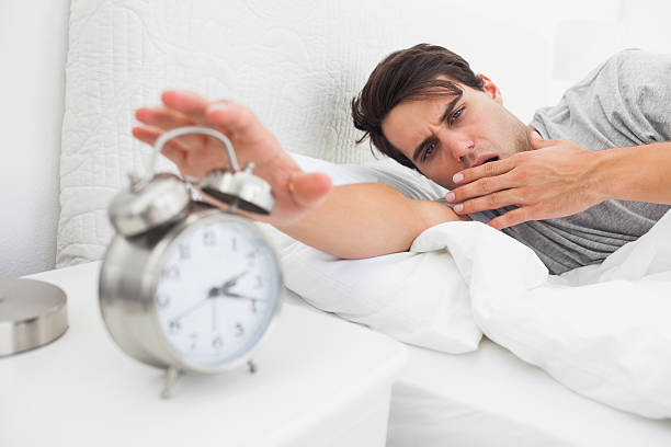istock Tired man turning off his alarm clock 462778693