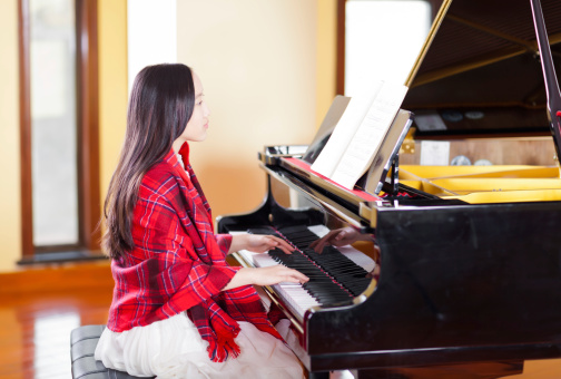 East asian teenager girl playing piano in the piano room