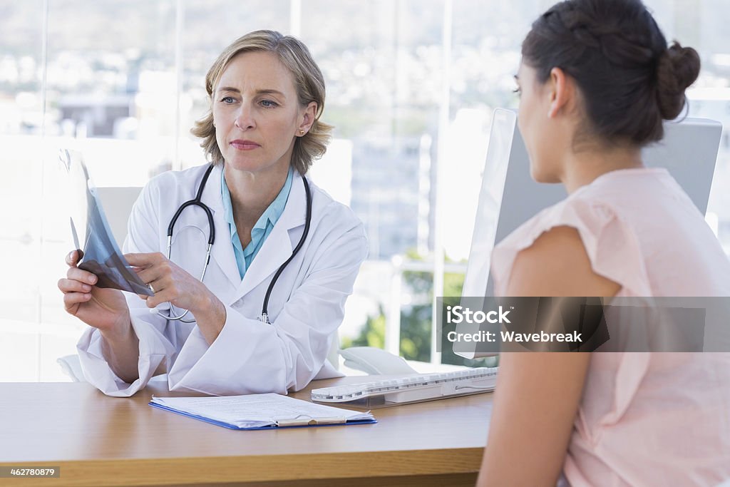 Doctor showing a x ray to her patient Doctor showing a x ray to her patient in her office 20-29 Years Stock Photo