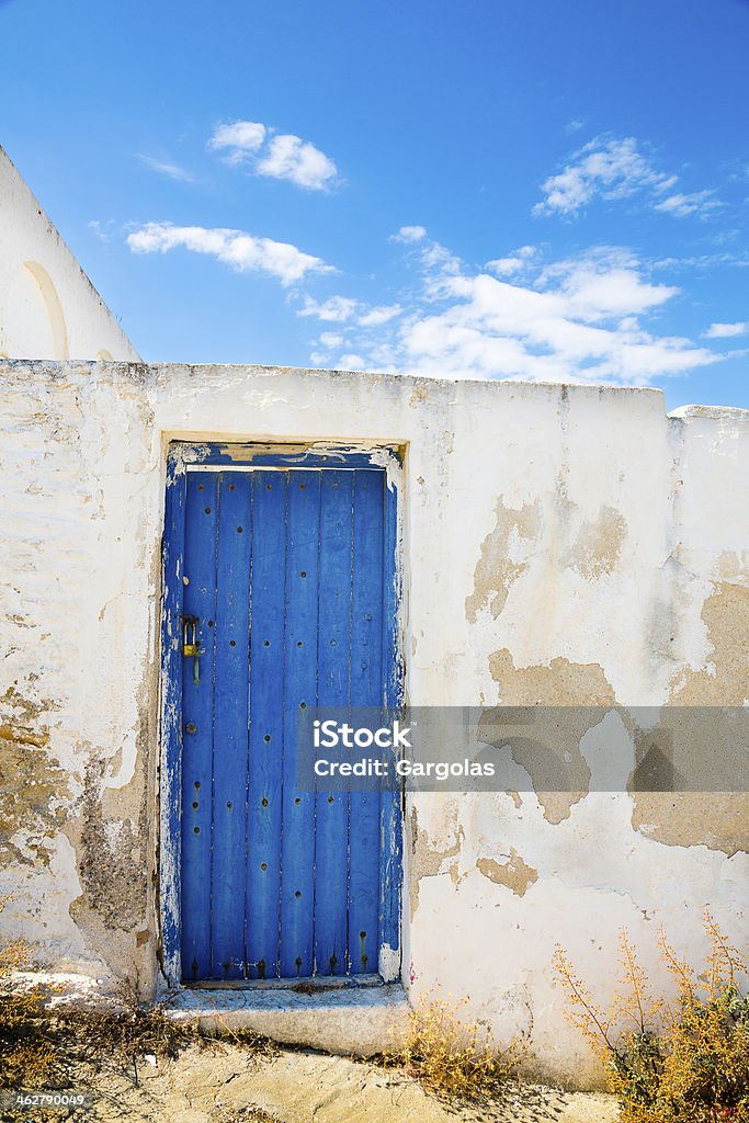 Blue door , Mykonos, Greece Blue door and white flaking paint on the wall in  Mykonos, Greece Aegean Islands Stock Photo