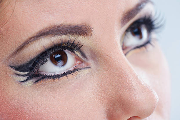 A close-up macro shot of a beautiful brown woman eye with mascara makeup that is looking away.