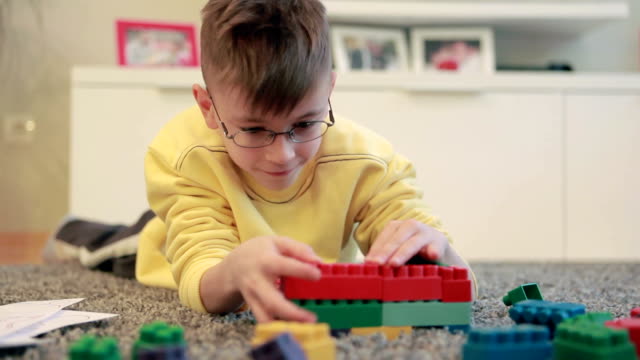Little boy playing on the livingroom floor with blocks set