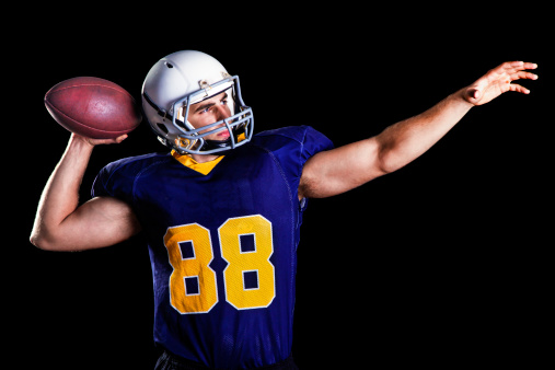 American football player preparing to toss the ball (isolated on black)