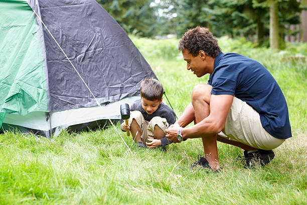 Father and son installing a tent for camping in countryside - Outdoors