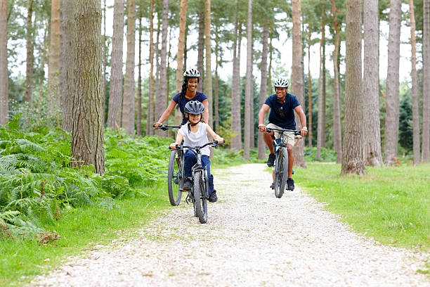 mixed race família desfrutando um passeio de bicicleta em campo - adventure african ethnicity rural scene day - fotografias e filmes do acervo