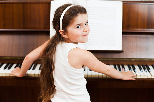 Little girl playing piano with sheet music.