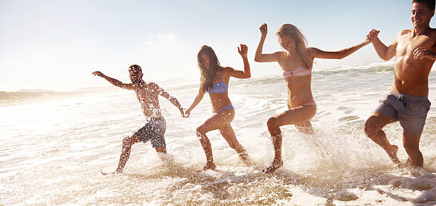 istock Two young couples splashing in water at beach 462873107