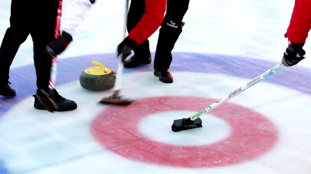 Curlers throw stones for curling on ice.