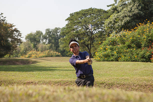 giovane maschio asiatico scheggiatura pallina da golf di bunker di sabbia - golf swing golf golf club chipping foto e immagini stock