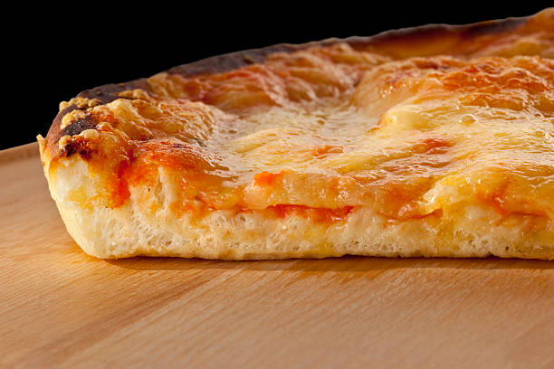 slice of pizza on wooden tray on a black background