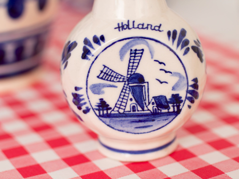 Small Delfts Blue vase, a part of a blue and white garage sale collection on a red and white checked tablecloth. Holland means The Netherlands.