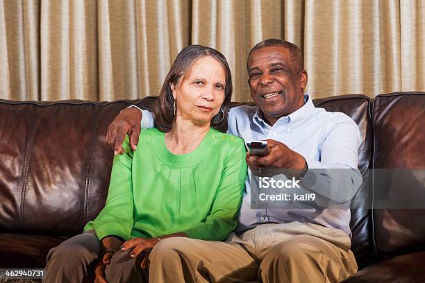 Senior African American Couple Watching Tv On Home On Couch Stock Photo - Download Image Now