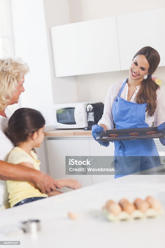 Mother taking cookies out of the oven Mother taking cookies out of the oven in kitchen 20-29 Years Stock Photo