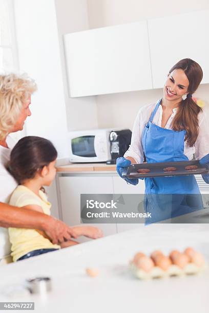Mother Taking Cookies Out Of The Oven Stock Photo - Download Image Now - 20-29 Years, 60-69 Years, Active Seniors