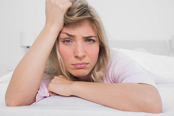 istock Tired blonde lying on bed looking at camera 462947239
