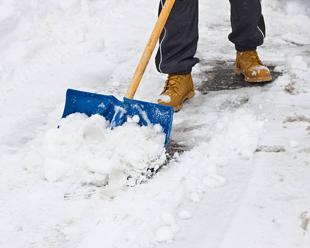 Foot shot of person shoveling snow with blue shovel Clearing snow with shovel after storm garden accessories stock pictures, royalty-free photos & images