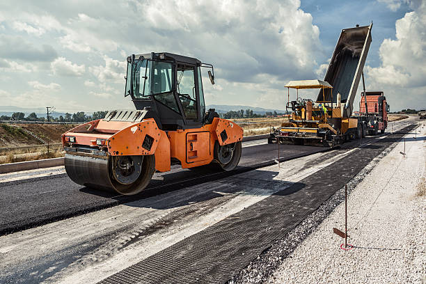 Road Construction Pavement machine laying fresh asphalt or bitumen on top of the gravel base during highway construction road construction photos stock pictures, royalty-free photos & images